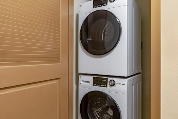 Two white front load washing machines stacked on top of each other.