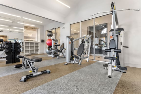a gym with weights and exercise equipment in a room with glass doors at Aston at Cinco Ranch, Texas, 77450