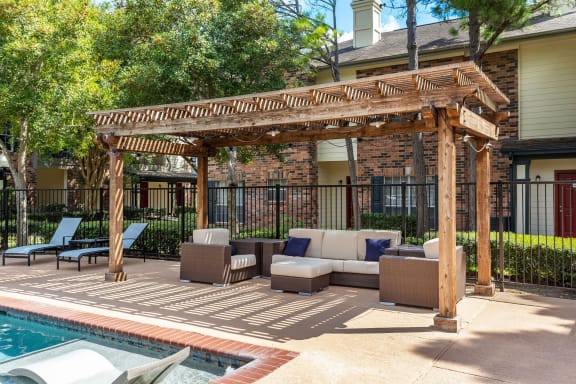 a covered patio with couches and chairs next to a pool