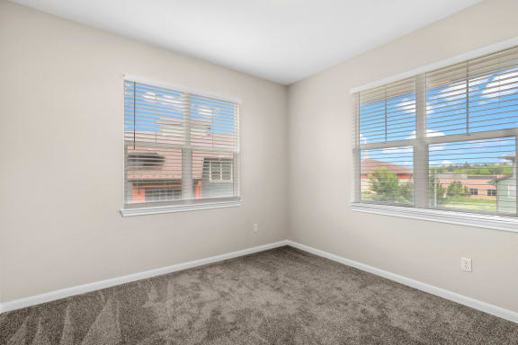 an empty bedroom with two windows and carpeting at Switchback on Platte Apartments, Littleton, CO 80120