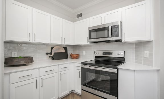 a kitchen with white cabinets and a stove and a microwave at Sladestone Shadow Creek, Pearland