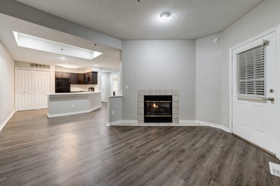 an empty living room with a fireplace and a kitchen at Ashford Belmar Apartments, Lakewood