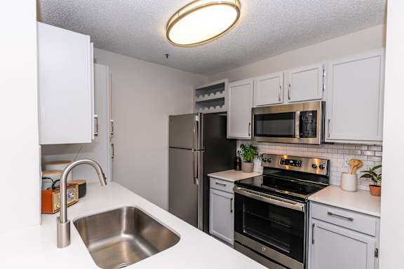 a kitchen with stainless steel appliances and white cabinets at Briarcliff Apartments, Georgia