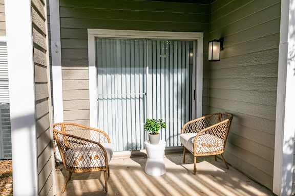 a porch with two rattan chairs and a vase with a plant at Briarcliff Apartments, Atlanta