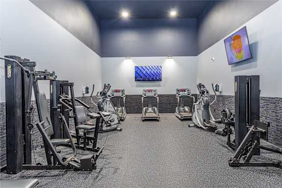 A gym with a variety of exercise equipment including treadmills, stationary bikes, and weight machines.