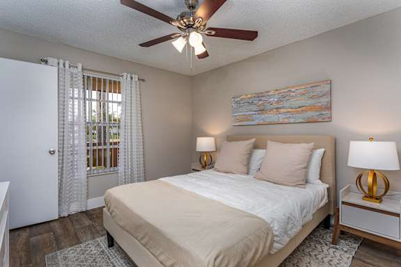 A bedroom with a bed, two lamps, and a painting on the wall.