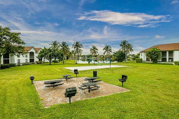 A park with a grassy area, benches, and a brick pathway.