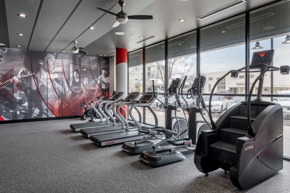 a gym with cardio equipment and a wall of windows with a view of a building at Mockingbird Flats, Dallas, TX, 75206