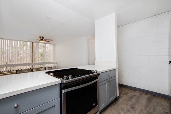 an empty kitchen with white counter tops and a black stove at Palms of Kilani Apartments, Hawaii
