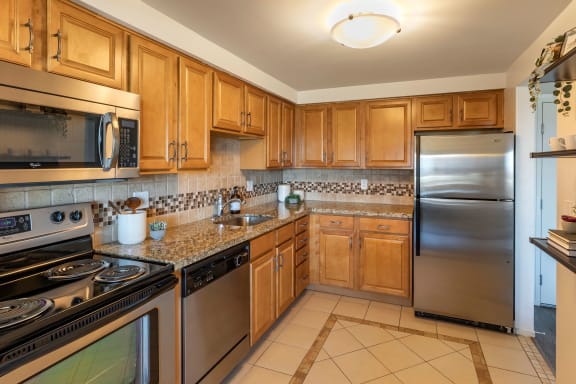 a kitchen with stainless steel appliances and wooden cabinets at The Rays at Vegas Towers Apartments, Las Vegas