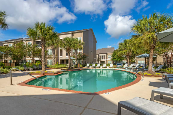 a swimming pool with palm trees and a building in the background at Summerwind, Pearland, 77584