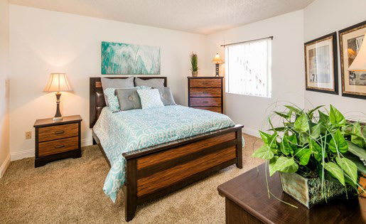 a bedroom with a bed and a potted plant at Sunset Winds Apartments, Henderson, NV 89014