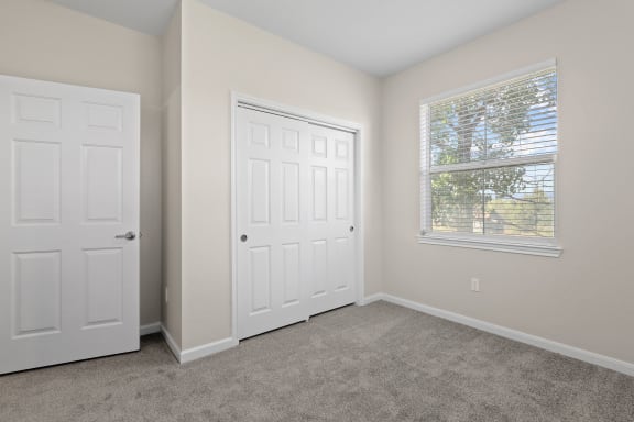 an empty bedroom with two doors and a window at Switchback on Platte Apartments, Littleton, 80120
