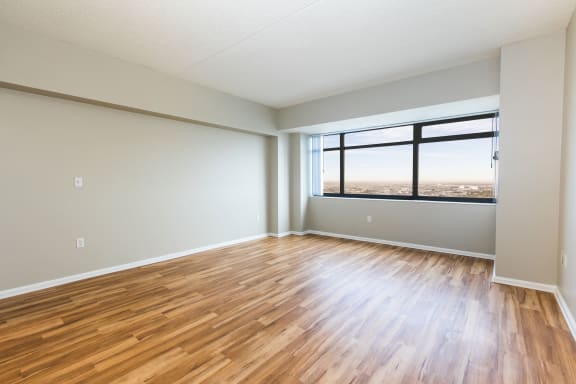 an empty living room with wood floors and a window at Apartments at Denver Place, Denver, 80202