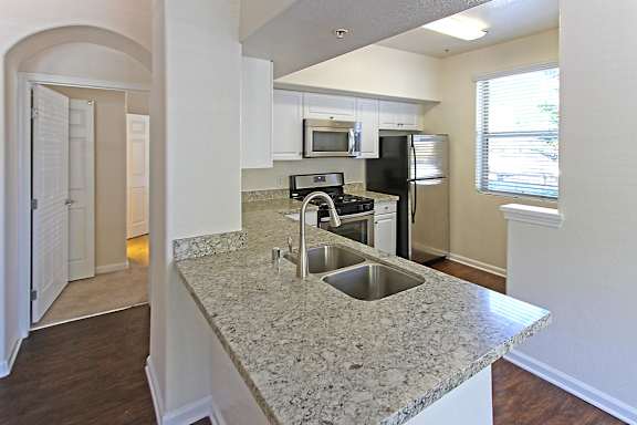 A kitchen with granite countertops and stainless steel appliances at The Kitt at Warner Center Apartments, Woodland Hills, CA
