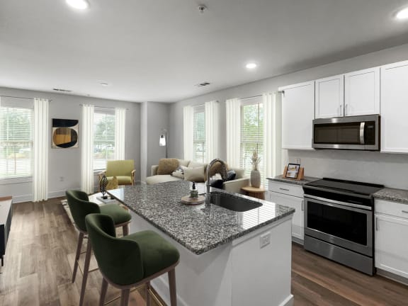 a renovated kitchen and living room with a granite counter top and white cabinets at The Merchant Apartments, Charleston