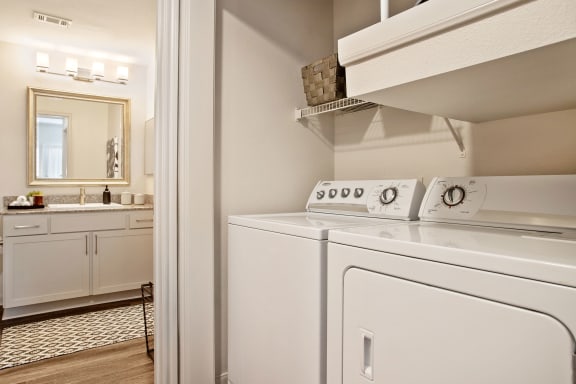 a washer and dryer in a laundry room with a sink and a mirror