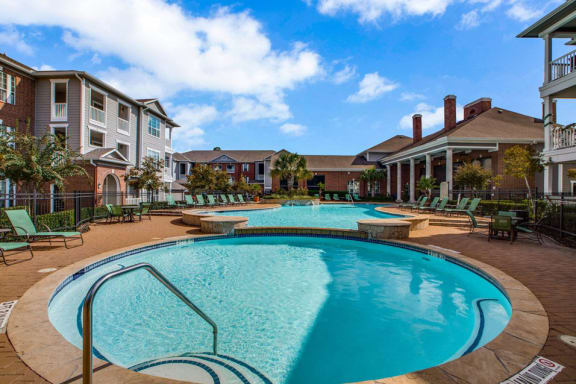 a large swimming pool with a building in the background at Volare at the Woodlands, The Woodlands