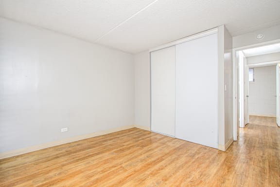 the living room and bedroom of an apartment with wood floors and white walls at Waikele Towers Apartments, Hawaii