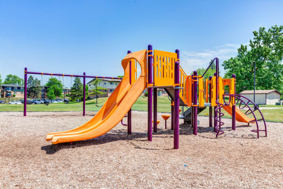 a playground with a yellow slide and other playground equipment at Willow Hill Apartments, Justice, IL, 60458