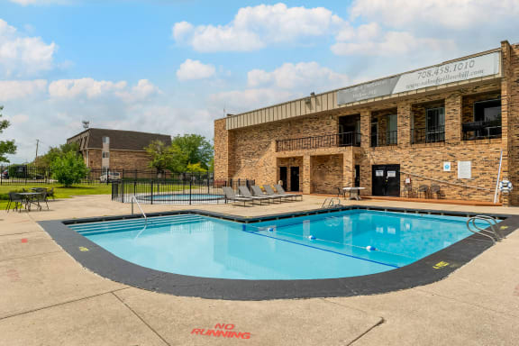 a swimming pool in front of a brick building with a pool at Willow Hill Apartments, Illinois, 60458