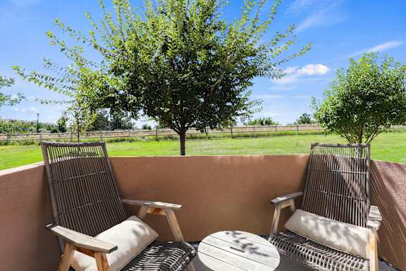 a patio with two chairs and a table and a tree at Ridge at Thornton Station Apartments, Thornton