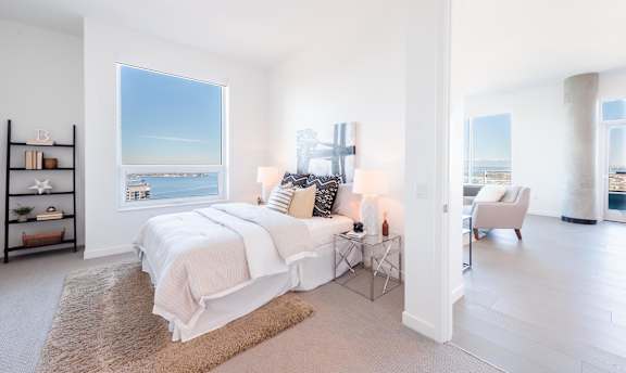 A bedroom with a large bed and a view of the ocean through the window.
