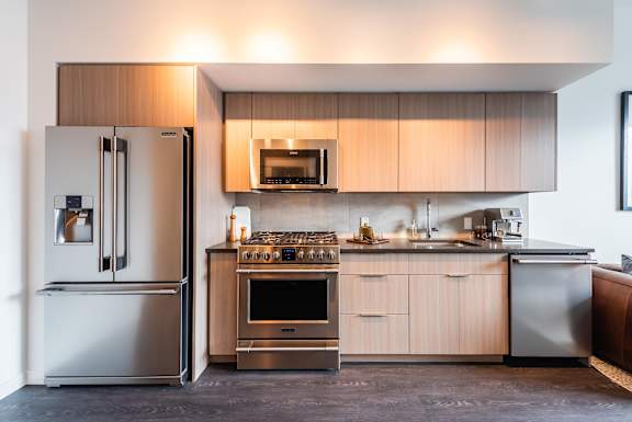A modern kitchen with a refrigerator, oven, and microwave.