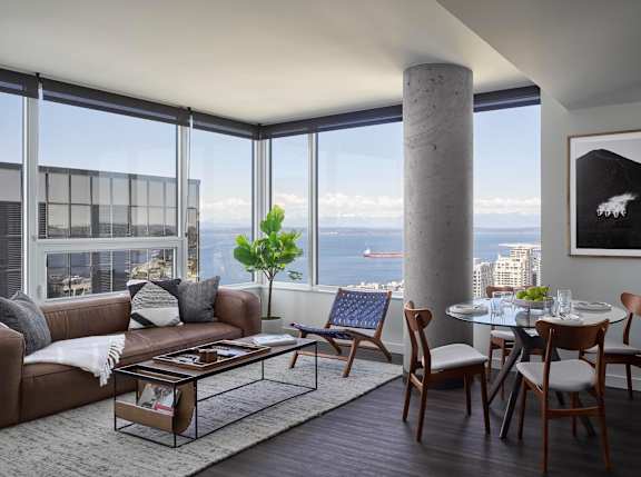 A living room with a couch, chairs, a coffee table, and a view of the city.