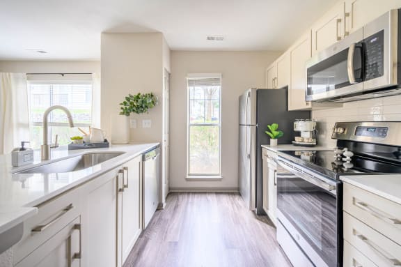a modern kitchen with stainless steel appliances and white cabinets at Ashford Green, Charlotte, 28262