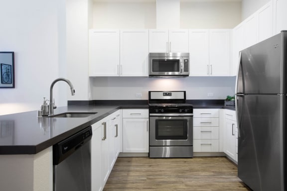 a kitchen with stainless steel appliances and white cabinets at Aventine, Hercules, California