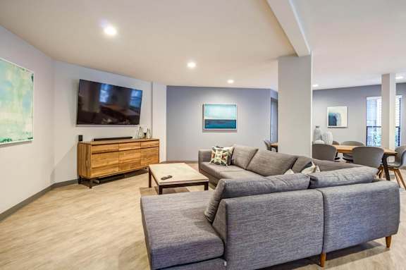 A living room with a grey couch and a wooden cabinet.