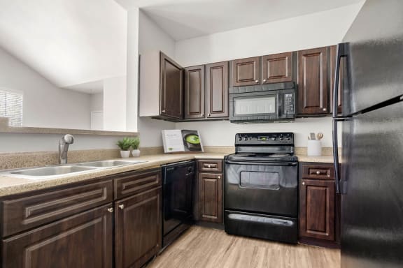 a kitchen with black appliances and wooden cabinets at Veranda at Centerfield, Houston, Texas