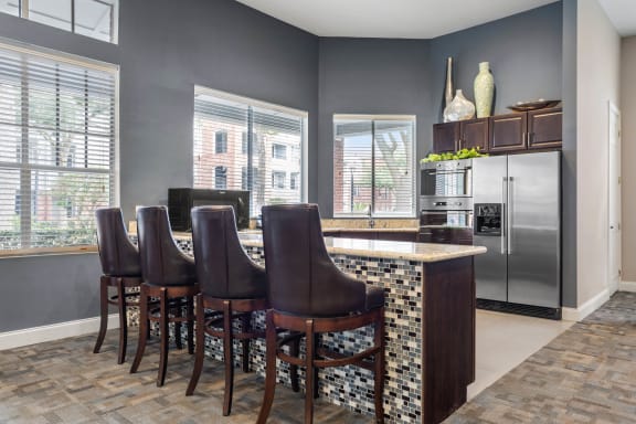 a kitchen with a bar and a stainless steel refrigerator at Veranda at Centerfield in Houston, Texas