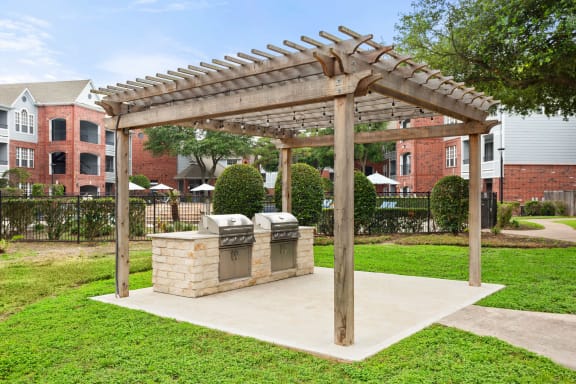 a pergola with a brick grill and bins in a park at Veranda at Centerfield in Houston, TX 77070