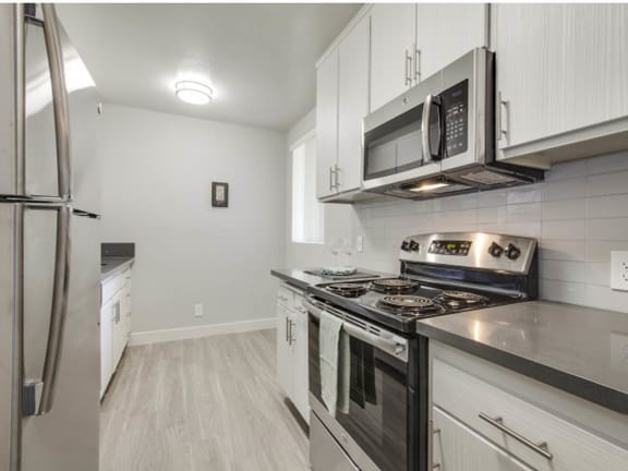 a kitchen with stainless steel appliances and white cabinets at Candlewood North, Northridge, 91324