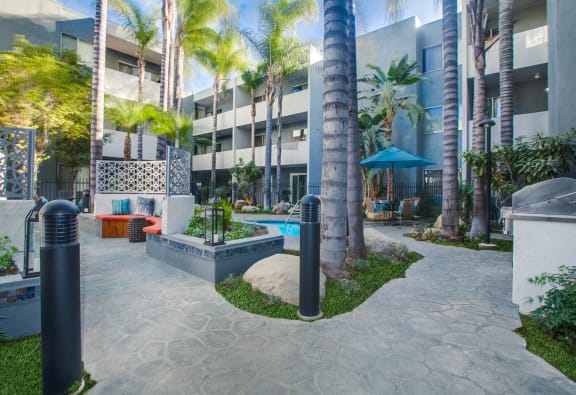 a courtyard with a pool and palm trees in front of a building at Candlewood North, Northridge, CA