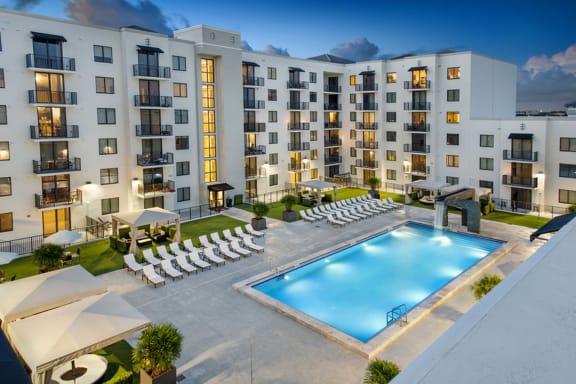an aerial view of an apartment building with a pool and chairs at District West Gables, FL 33155