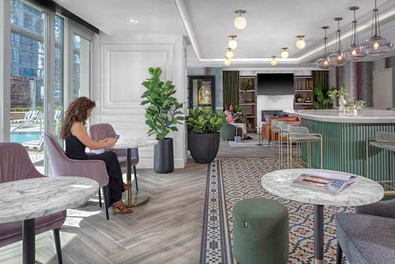 woman is sitting in a chair with plant  at Flair Tower Apartments, Chicago, IL 60654