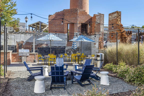 a patio with blue and yellow chairs and umbrellas at Highland Mill Lofts, Charlotte, 28205