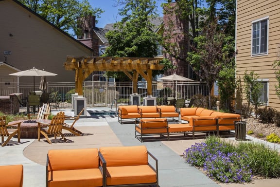 a patio with orange couches and chairs and umbrellas at Skyview in Westminster, CO 80234