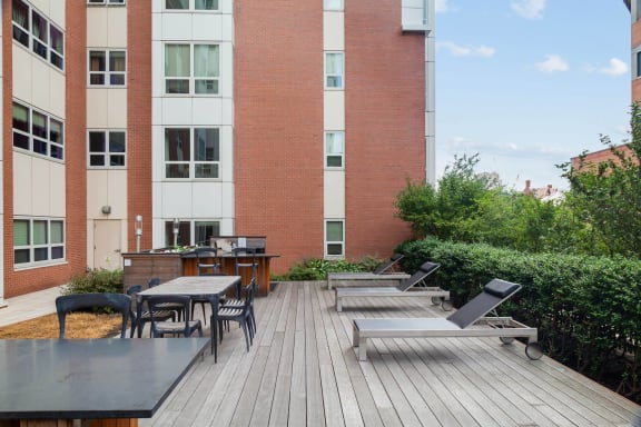 a patio with tables and chairs in front of a brick building at Amelia, Massachusetts, 02169