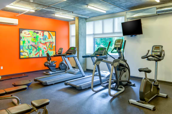 a room filled with cardio equipment and a flat screen tv at The Parker, Portland 97209