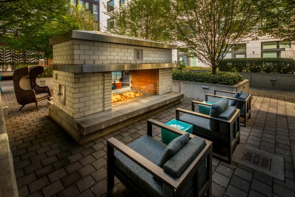 a patio with a fireplace and lounge chairs at The Parker, Portland, Minnesota  97209