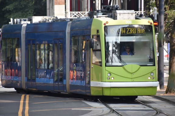 a green and blue tram is on the tracks at The Parker Apartments, Portland, 97209