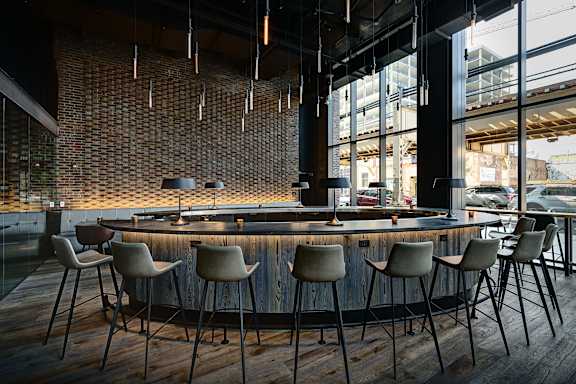 A bar with a brick wall and wooden chairs. at The Mason Apartments, Chicago, IL