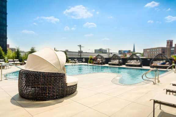 A white sun umbrella is on a chair by a pool. at The Mason Apartments, Chicago, IL, 60607
