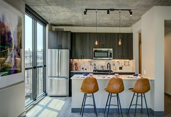 A kitchen with a bar stool and a fridge. at The Mason Apartments, Chicago