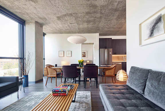 A modern living room with a grey sofa and a wooden coffee table. at The Mason Apartments, Chicago, IL
