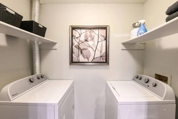 a white laundry room with two washers and a painting on the wall at Verona, Littleton, Colorado